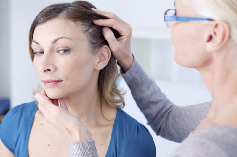 woman about to have strands of hair removed for a drug test