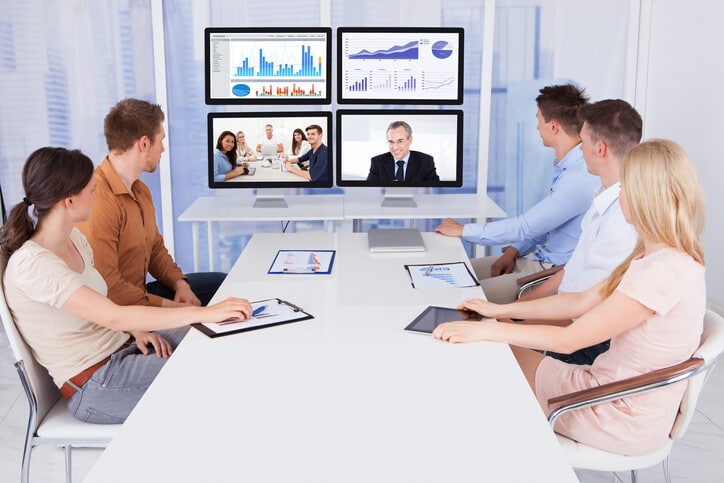 Group of people in meeting sitting at a desk and looking at monitors